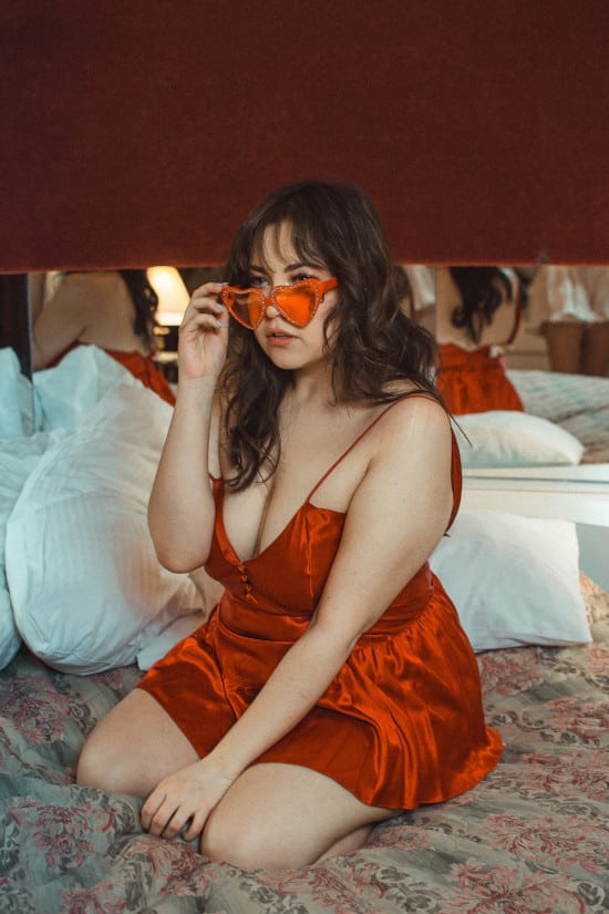 Junge Frau in roter Seide mit herzförmiger Sonnenbrille