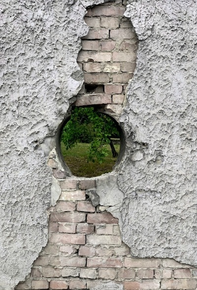 Kreisrundes Loch in verwitterter Mauer als Sinnbild für Analsex